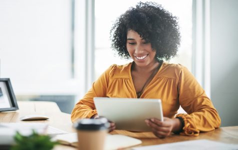 Cropped shot of an attractive young businesswoman sitting alone in her home office and using a tablet